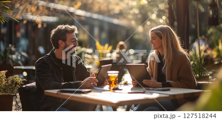 a man and woman collaborating on a project in an urban park coworking space, stylish outdoor furniture and public Wi Fi area visible, blank right side for text, bright clear light 127518244