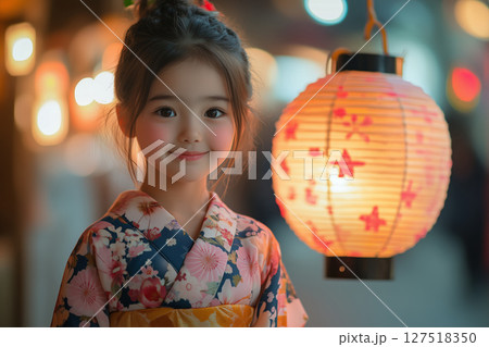 a young girl wearing a floral yukata, holding a lit lantern at an Obon festival, vibrant paper decorations 127518350