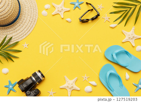 Summer accessories framing vibrant yellow background for travel planning 127519203
