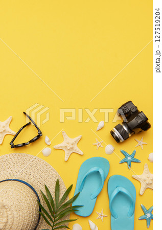 Summer holiday accessories lying on vibrant yellow background with copy space 127519204