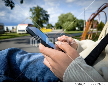 Close-up of young caucasian man using mobile phone at the skatepark. young man using a mobile phone. hands of unrecognizable man typing online message using mobile phone 127519737