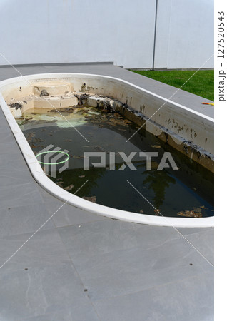 Dirty abandoned swimming pool with stagnant water and debris. 127520543