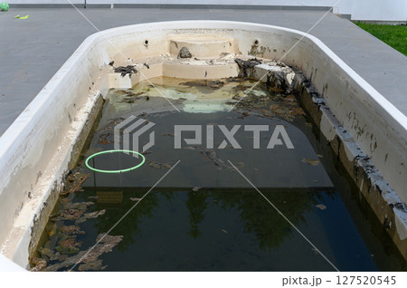 Dirty abandoned swimming pool with stagnant water and debris. Dirty abandoned swimming pool with stagnant water and debris. 127520545