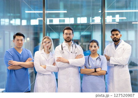 A diverse medical team stands together, arms crossed, conveying unity and expertise in a modern healthcare setting. A diverse medical team stands together, arms crossed, conveying unity and expertise in a modern healthcare setting. 127520907