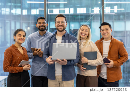 A diverse team of colleagues smiles with joy and confidence while looking at the camera in the office. Collaboration. A diverse team of colleagues smiles with joy and confidence while looking at the camera in the office. Collaboration. 127520938