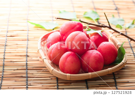笊に盛り付けた早生スモモ 127521928