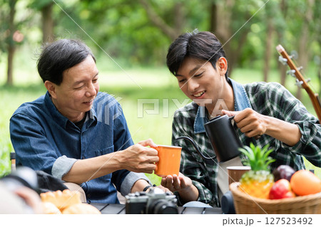 Family bonding outdoors. A father and son sharing drinks and laughter in nature. 127523492