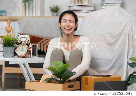 Moving joy. Happy woman unboxing new items in her living space. 127523548