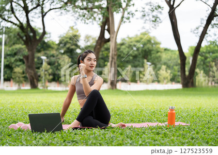 Yoga practice in nature. Young woman meditating outdoors with laptop and water bottle. Yoga practice in nature. Young woman meditating outdoors with laptop and water bottle. 127523559