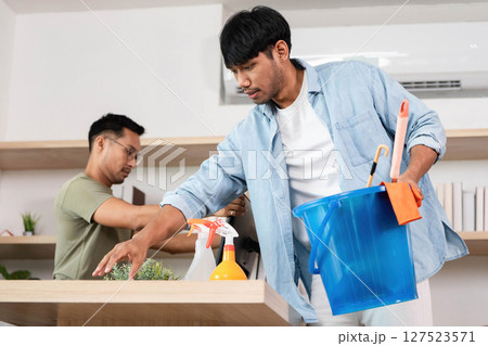 Home Cleaning and Organization. Two men collaborating on cleaning and organizing a modern workspace. 127523571
