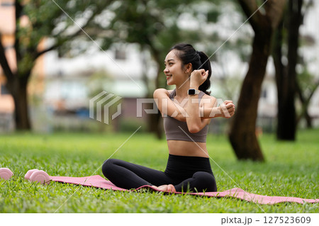 Yoga practice outdoors. Young woman stretching and enjoying wellness in a green park. 127523609