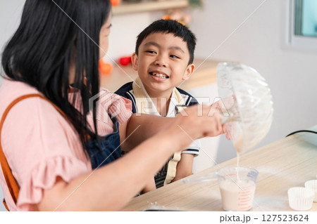 Family Moments in Baking. A mother and son sharing laughter while preparing batter. 127523624