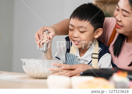 Family Cooking Together. A mother and son enjoying a fun baking session in the kitchen. Family Cooking Together. A mother and son enjoying a fun baking session in the kitchen. 127523628
