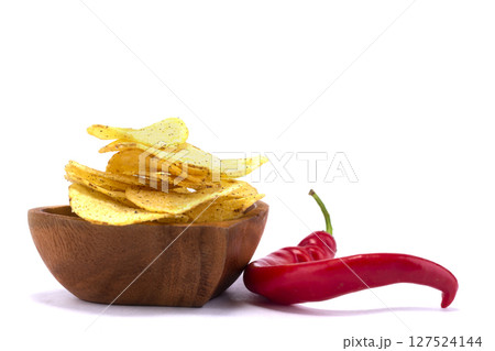 Chips with red pepper on a wooden plate close-up. 127524144