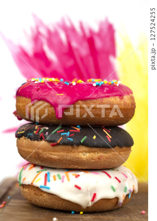 Creative sweet food. A stack of glazed colorful assorted donuts on a bright watercolor painted background. 127524255