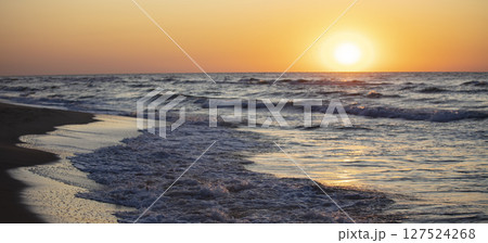 Beautiful sunset over the sea. Red sun and waves. 127524268