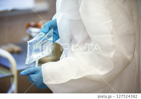 The doctor's hands in rubber gloves hold the dropper solution. The doctor's hands in rubber gloves hold the dropper solution. 127524382