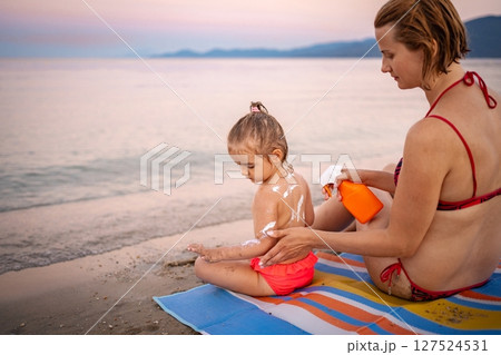 Mother applying sunscreen to child on Greek beach 127524531
