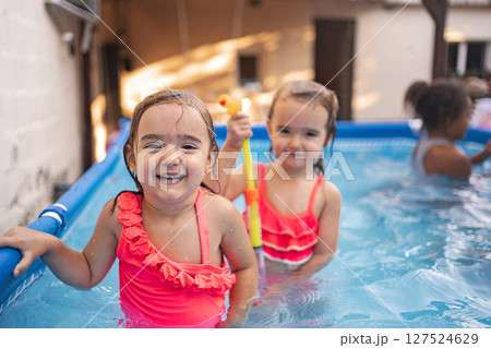 Twins sisters enjoy swimming in a backyard pool on a sunny day 127524629