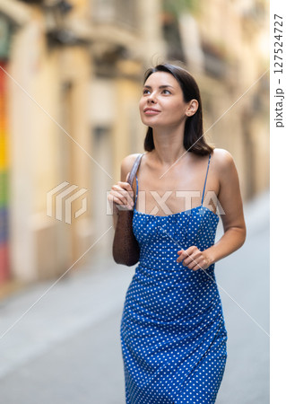 Young woman looks around on city street 127524727