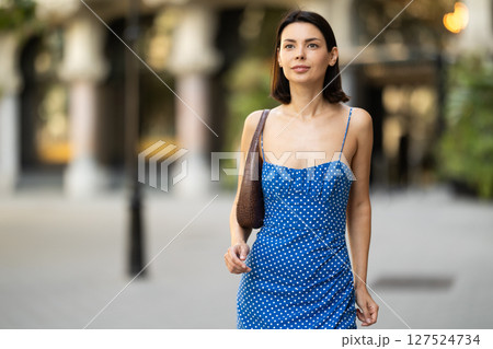 Young brunette girl in blue dress walking along the streets of the historical center of city Young brunette girl in blue dress walking along the streets of the historical center of city 127524734
