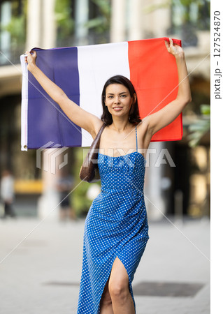 Girl waving France flag on street of summer city 127524870