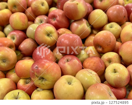 Box filled with fresh natural bio organic red yellow coloured apples placed on counter in local food market. Close-up. Box filled with fresh natural bio organic red yellow coloured apples placed on counter in local food market. Close-up. 127524895