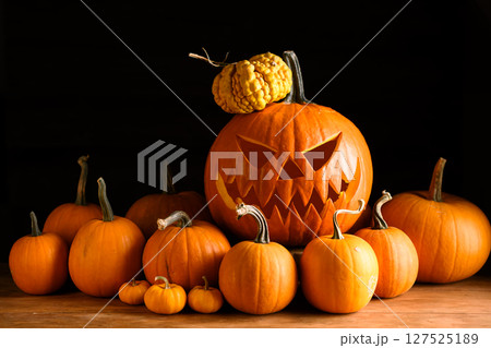 Scary jack-o'-lantern in center of tiny orange pumpkins 127525189