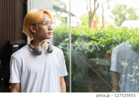 Asian teenager man looking through window and thinking Asian teenager man looking through window and thinking 127525655