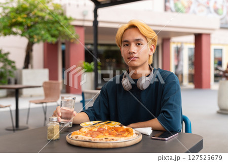 Thai gay teen male enjoying pepperoni pizza in outdoor restaurant 127525679
