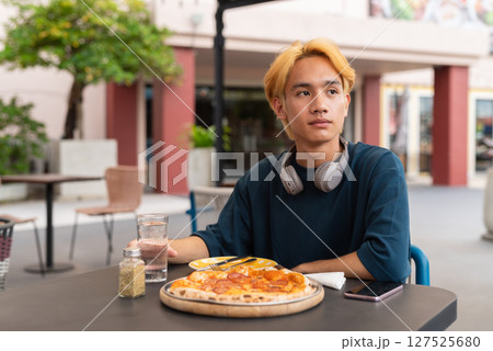 Thai gay teen male enjoying pepperoni pizza in outdoor restaurant Thai gay teen male enjoying pepperoni pizza in outdoor restaurant 127525680