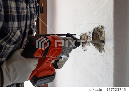 Carpenter electrician working with demolition hammer. Electricity. 127525746