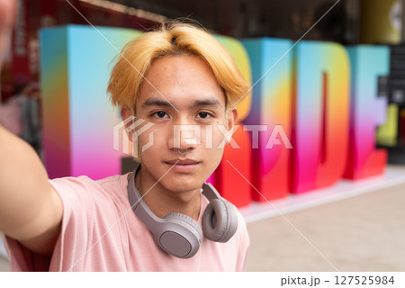 Gay influencer taking selfie during pride outdoors in city 127525984