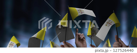 Vatican flags in their hands on a blurred urban background 127526440