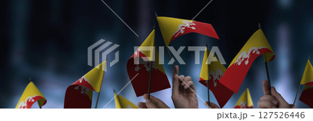 Bhutan flags in their hands on a blurred urban background Bhutan flags in their hands on a blurred urban background 127526446