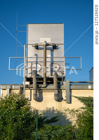 Large industrial cooling system with exposed pipes mounted on building wall 127526828