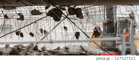 Close-up view of crumbling bridge structure demolition in Magdeburg Damaschkeplatz  exposed steel rebar falling concrete chunks. Rubble piles and demolition machinery emphasize destruction progress 127527521