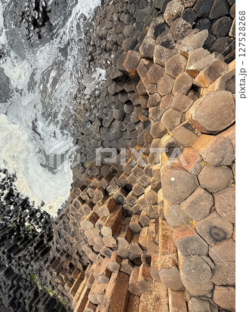 Giant's Causeway is a UNESCO World Heritage Site on Northern Ireland's Antrim Coast, famous for hexagonal stones by volcanic activity and beautiful coast. 127528268