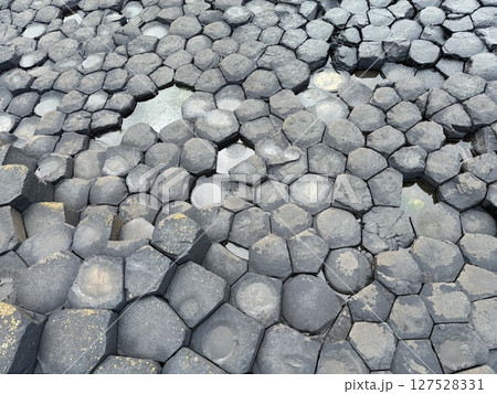 Giant's Causeway is a UNESCO World Heritage Site on Northern Ireland's Antrim Coast, famous for hexagonal stones by volcanic activity and beautiful coast. 127528331