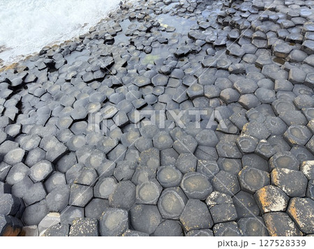 Giant's Causeway is a UNESCO World Heritage Site on Northern Ireland's Antrim Coast, famous for hexagonal stones by volcanic activity and beautiful coast. 127528339