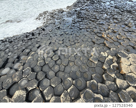 Giant's Causeway is a UNESCO World Heritage Site on Northern Ireland's Antrim Coast, famous for hexagonal stones by volcanic activity and beautiful coast. 127528340
