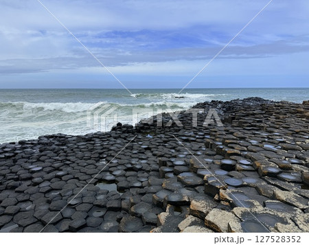 Giant's Causeway is a UNESCO World Heritage Site on Northern Ireland's Antrim Coast, famous for hexagonal stones by volcanic activity and beautiful coast. 127528352