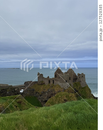 Dunluce Castle, perched on Northern Ireland's rugged Antrim Coast, showcases dramatic medieval ruins against windswept cliffs. Its weathered stone walls and sea views evoke history and mystery, ideal  127528385