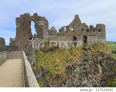 Dunluce Castle, perched on Northern Ireland's rugged Antrim Coast, showcases dramatic medieval ruins against windswept cliffs. Its weathered stone walls and sea views evoke history and mystery, ideal Dunluce Castle, perched on Northern Ireland's rugged Antrim Coast, showcases dramatic medieval ruins against windswept cliffs. Its weathered stone walls and sea views evoke history and mystery, ideal 127528392