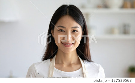 キッチンで笑顔のエプロンをした若い女性 キッチンで笑顔のエプロンをした若い女性 127529568
