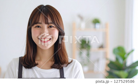 部屋でキッチンに立つエプロンをした若い女性 127529586