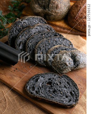 Fresh baked black charcoal sourdough ciabatta bread sliced on wooden board. Fresh baked black charcoal sourdough ciabatta bread sliced on wooden board. 127530312