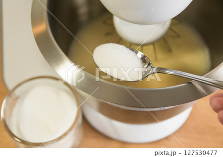 Metal spoon with sugar near metal biscuit dough of electric mixer. Metal spoon with sugar near metal biscuit dough of electric mixer. 127530477