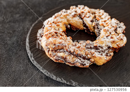 Brezel handcrafted sweet, pastry delicious snack, on slate stone plate round, dark background, selective focus  127530956
