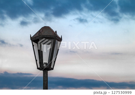 Old street lamp rusty without light bulb close-up against cloudy sky Old street lamp rusty without light bulb close-up against cloudy sky 127530999